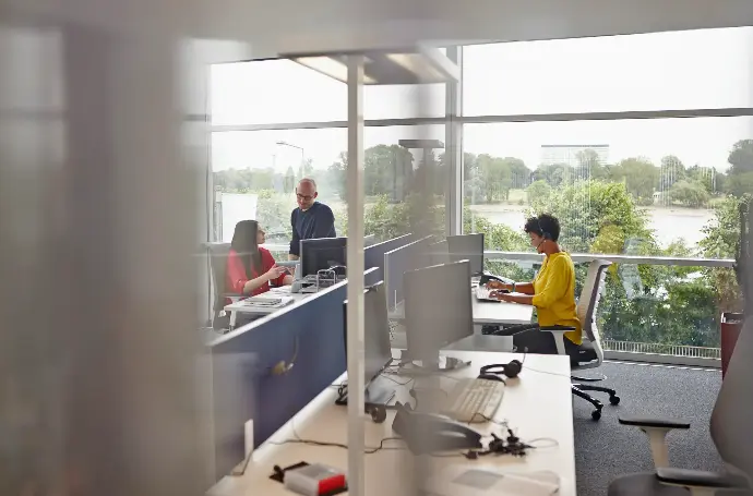 3 personas en una oficina con ventanal trabajando
