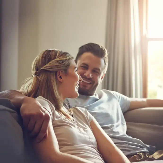Pareja sentada en  el sofá sonriendo